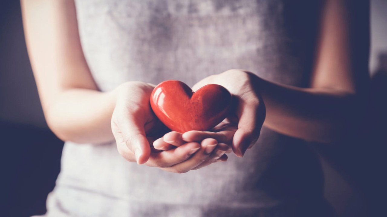 A woman is holding a red heart in her hands.