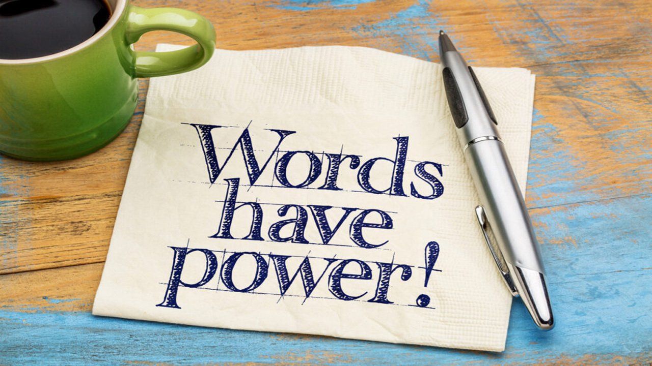 A napkin with the words `` words have power '' written on it next to a pen and a cup of coffee.
