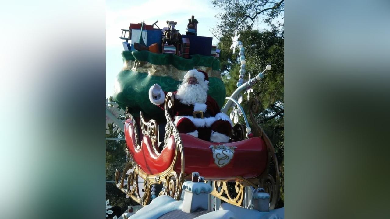Santa claus is sitting in a sleigh with a train in the background.
