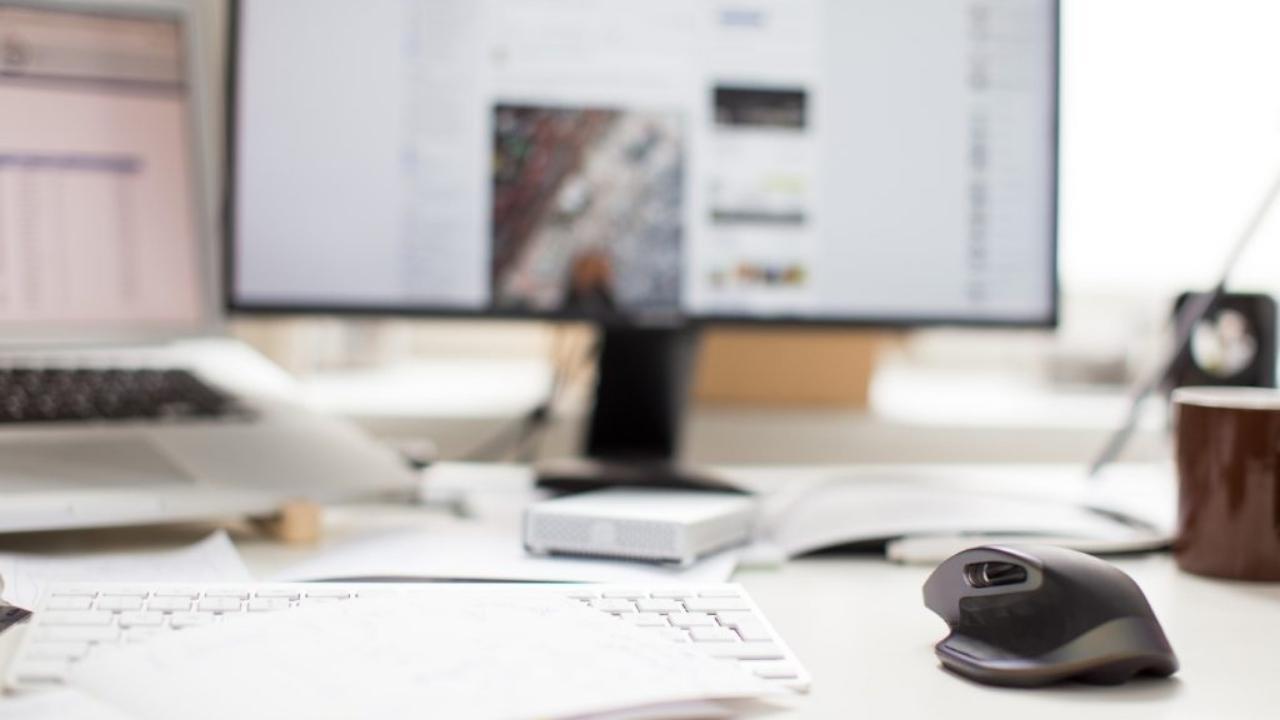 A computer mouse is sitting on a desk in front of a computer monitor.