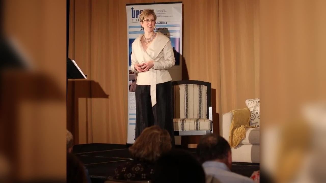 A woman is standing on a stage giving a presentation