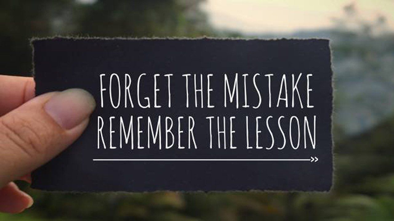 A person is holding a card that says forget the mistake remember the lesson