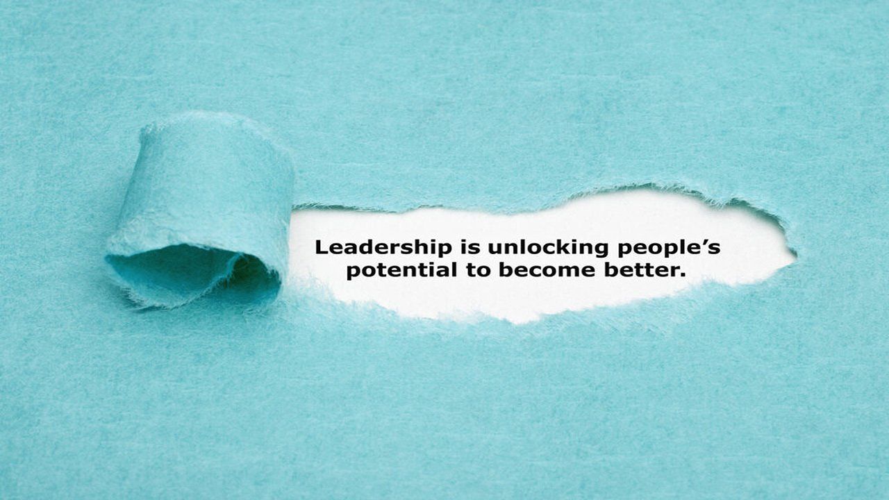 A piece of torn paper with a quote on it that says leadership is unlocking people 's potential to become better