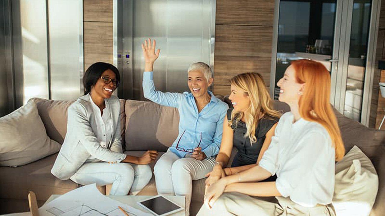 A group of women are sitting on a couch giving each other a high five.