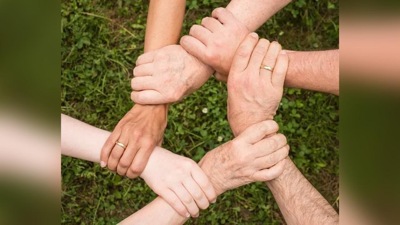 A group of people are putting their hands together in a circle.