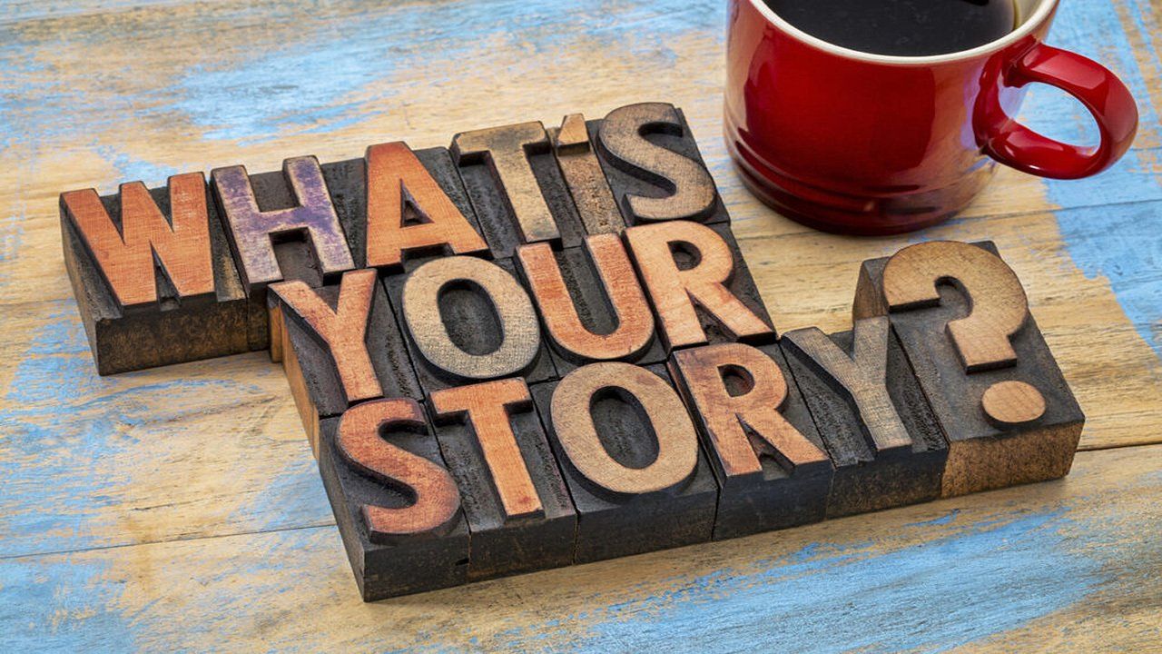 A wooden sign that says `` what 's your story '' next to a cup of coffee.