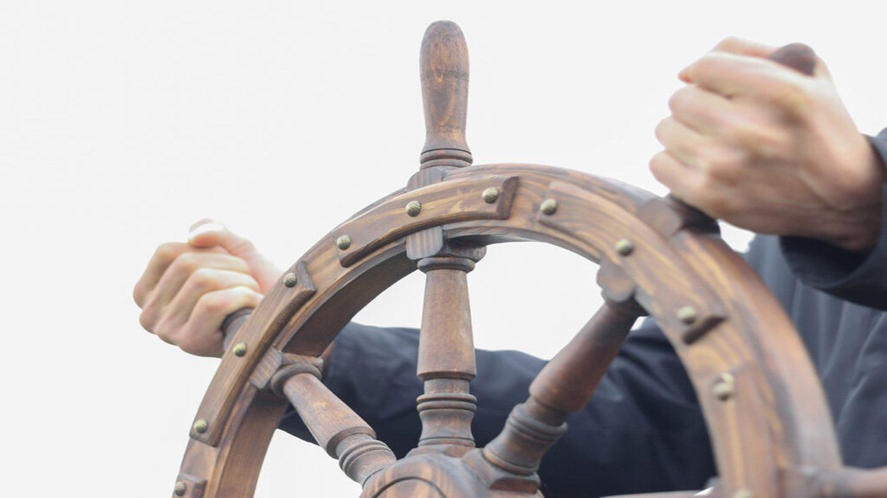 A man is holding a wooden steering wheel in his hands.