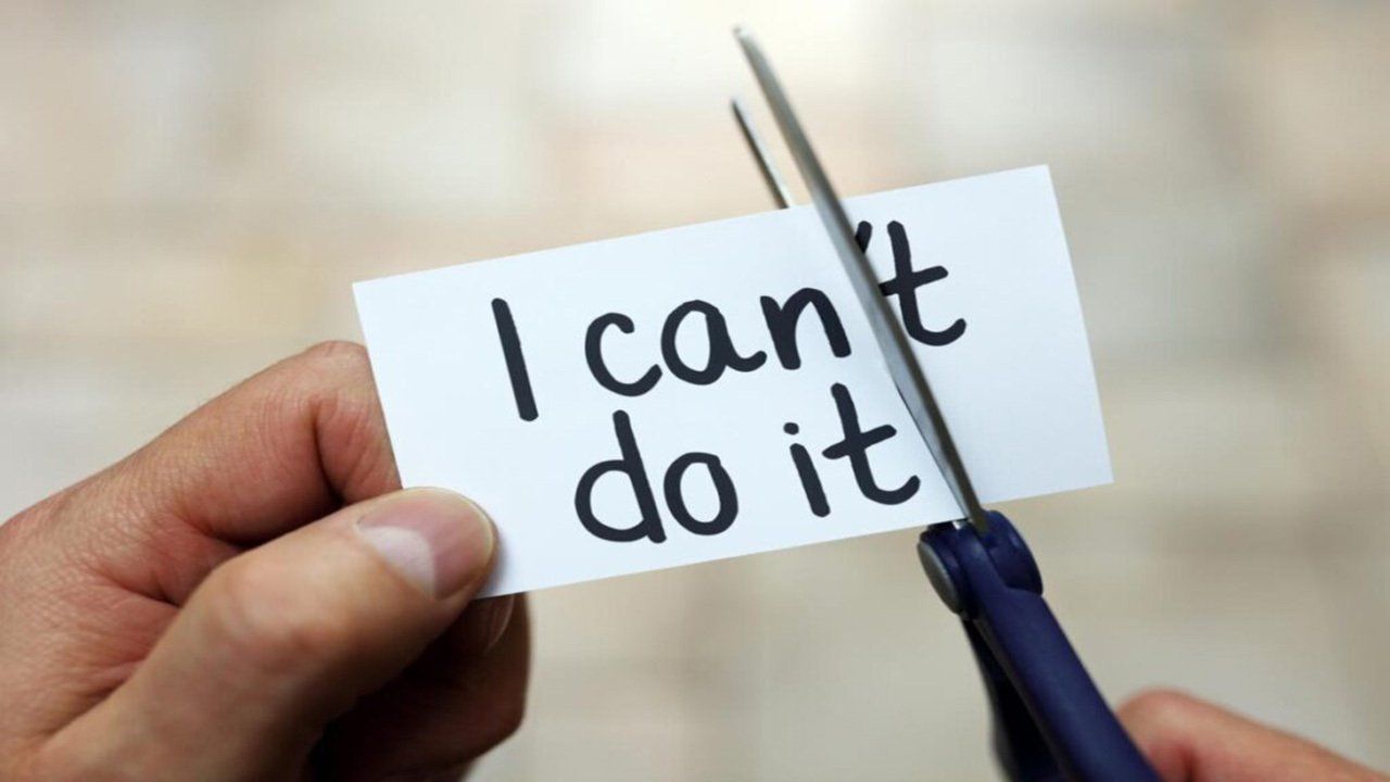 A person is cutting a piece of paper that says i can t do it