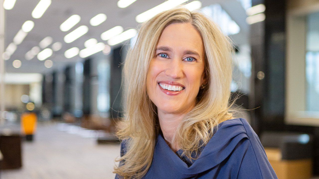 A woman in a blue shirt is smiling for the camera.