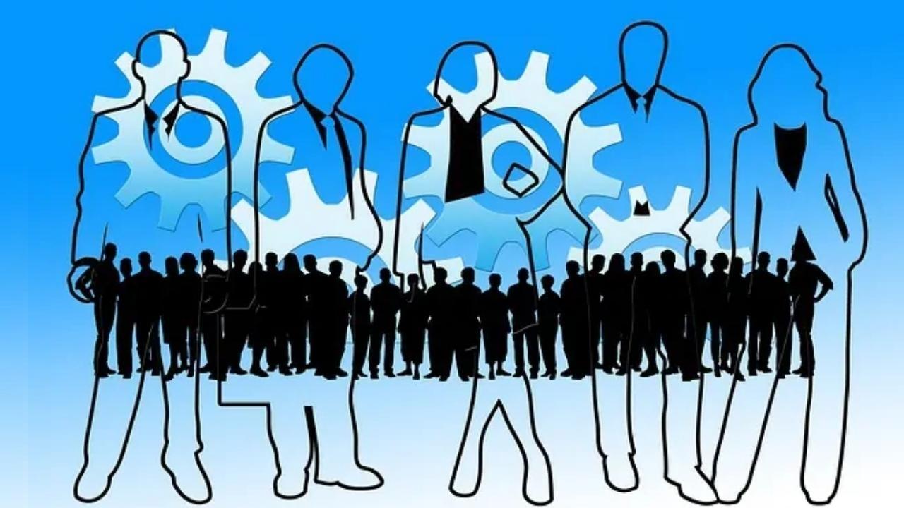 A group of people standing in front of gears on a blue background