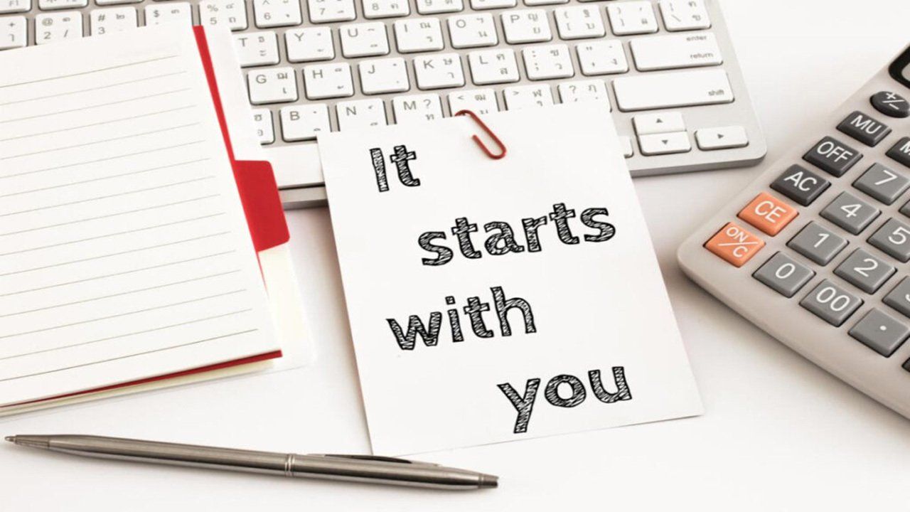 A note that says it starts with you next to a calculator