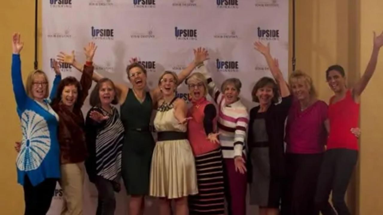 A group of women are posing for a picture with their arms in the air.