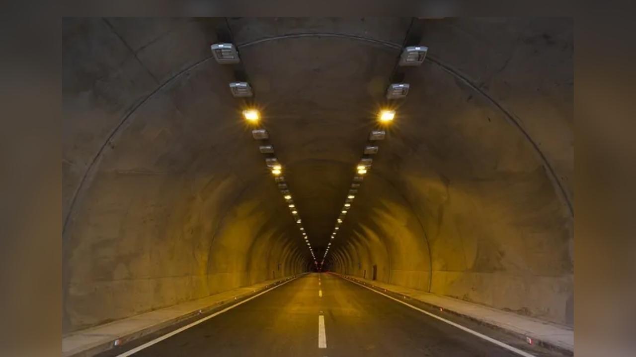 A road is going through a tunnel with lights on the walls.
