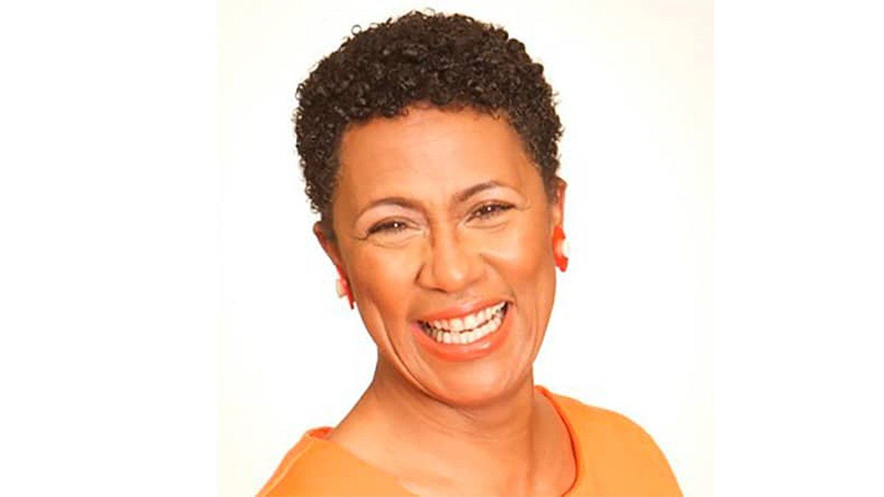 A woman in an orange shirt is smiling for the camera.
