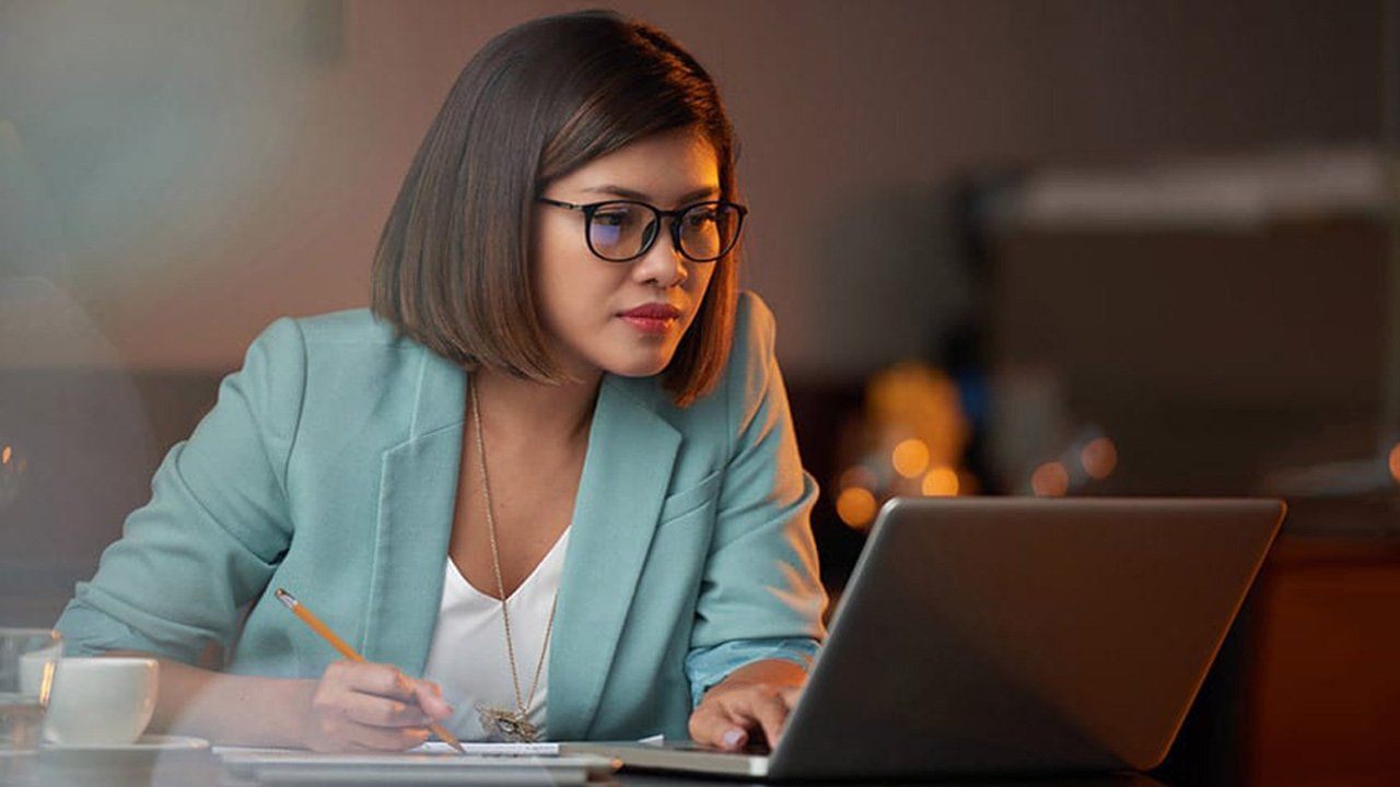 A woman is sitting at a table using a laptop computer.