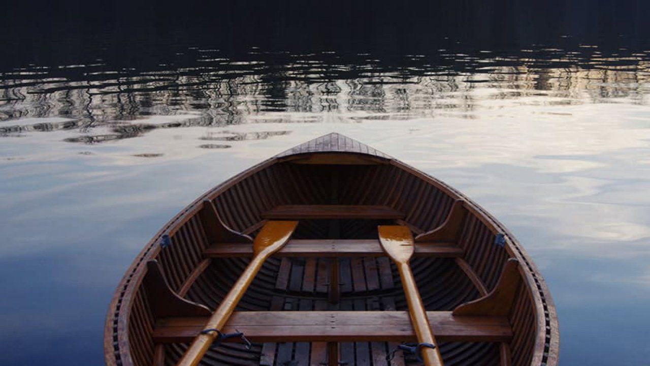 A wooden boat with two oars in the water.