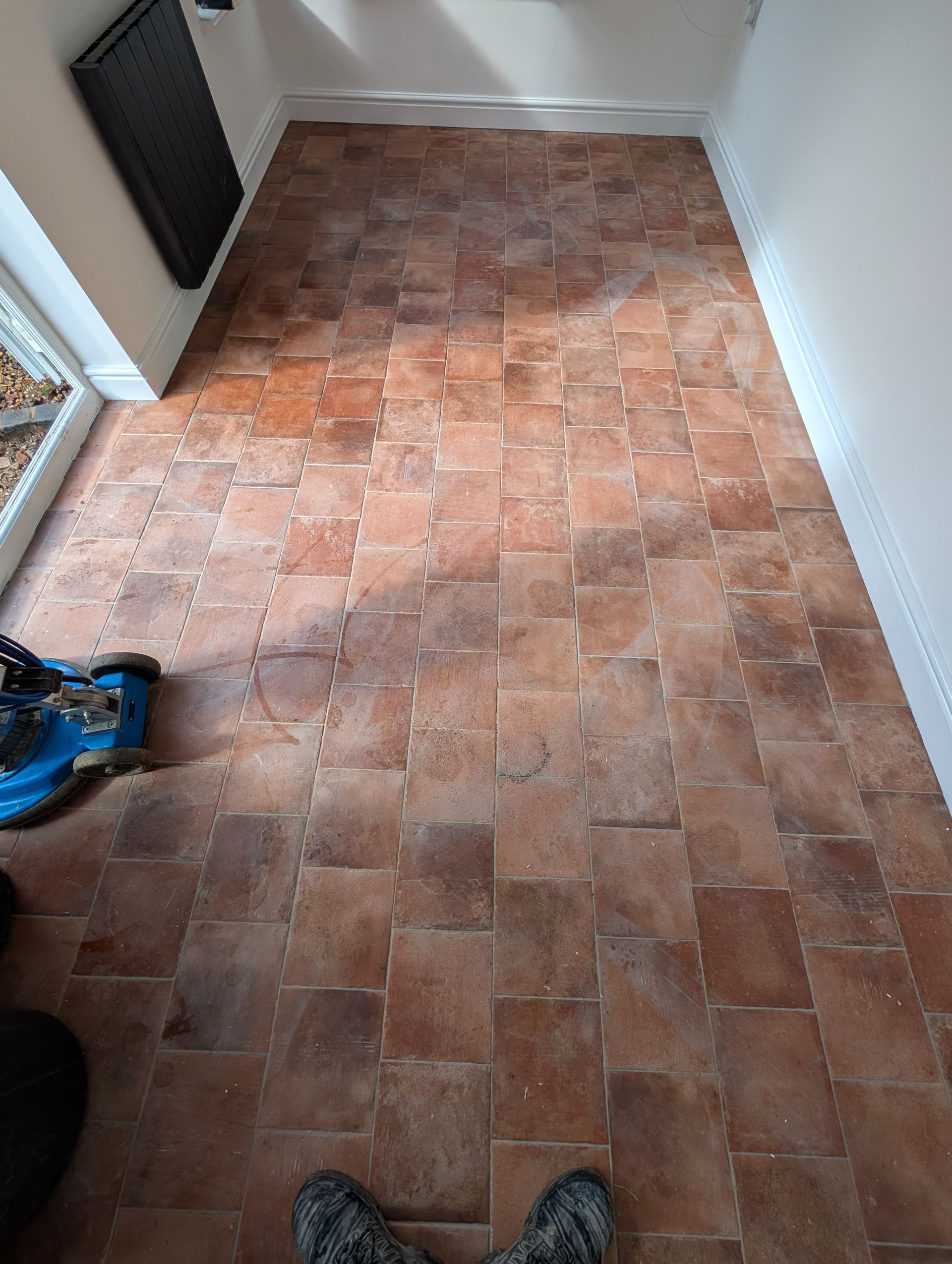 Terracotta floor covered in post-construction dust before deep cleaning.