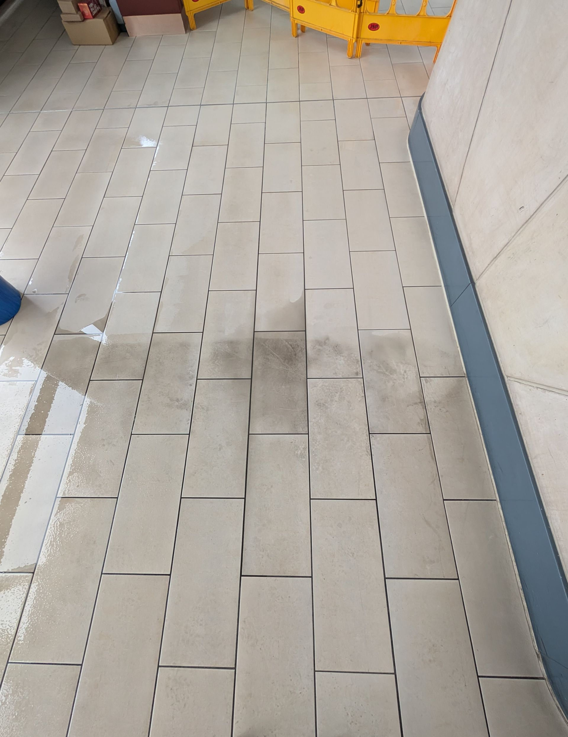 Detailed before-and-after comparison of lobby tiles at No.1 Deansgate Manchester — professional deep clean by Quality Tile Care removing ingrained dirt, restoring colour, and enhancing stone texture in communal area.