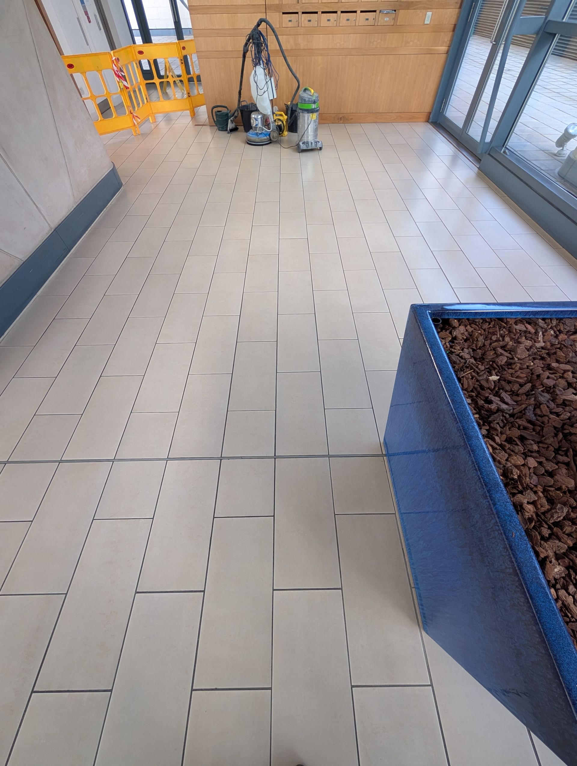 Cleaned corridor floor at No.1 Deansgate Manchester after tile and grout restoration by Quality Tile Care, featuring bright, even finish and revived grout lines across high-traffic communal area.