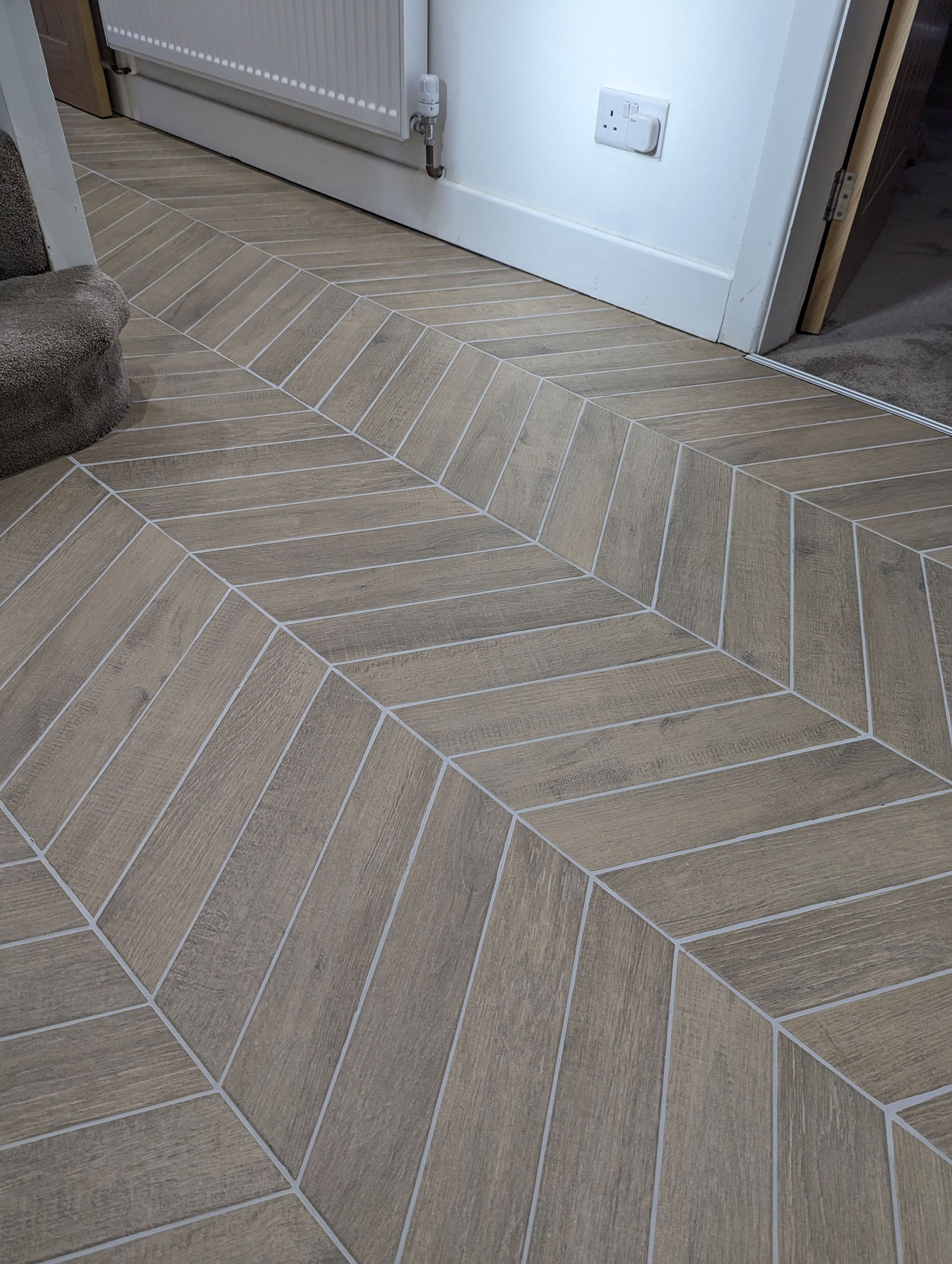 A close up of a wooden effect porcelain floor with a chevron pattern.