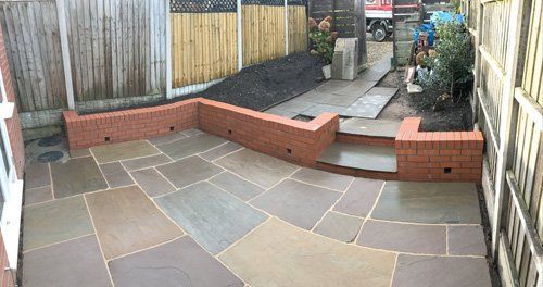 freshly laid paving with small brick wall
