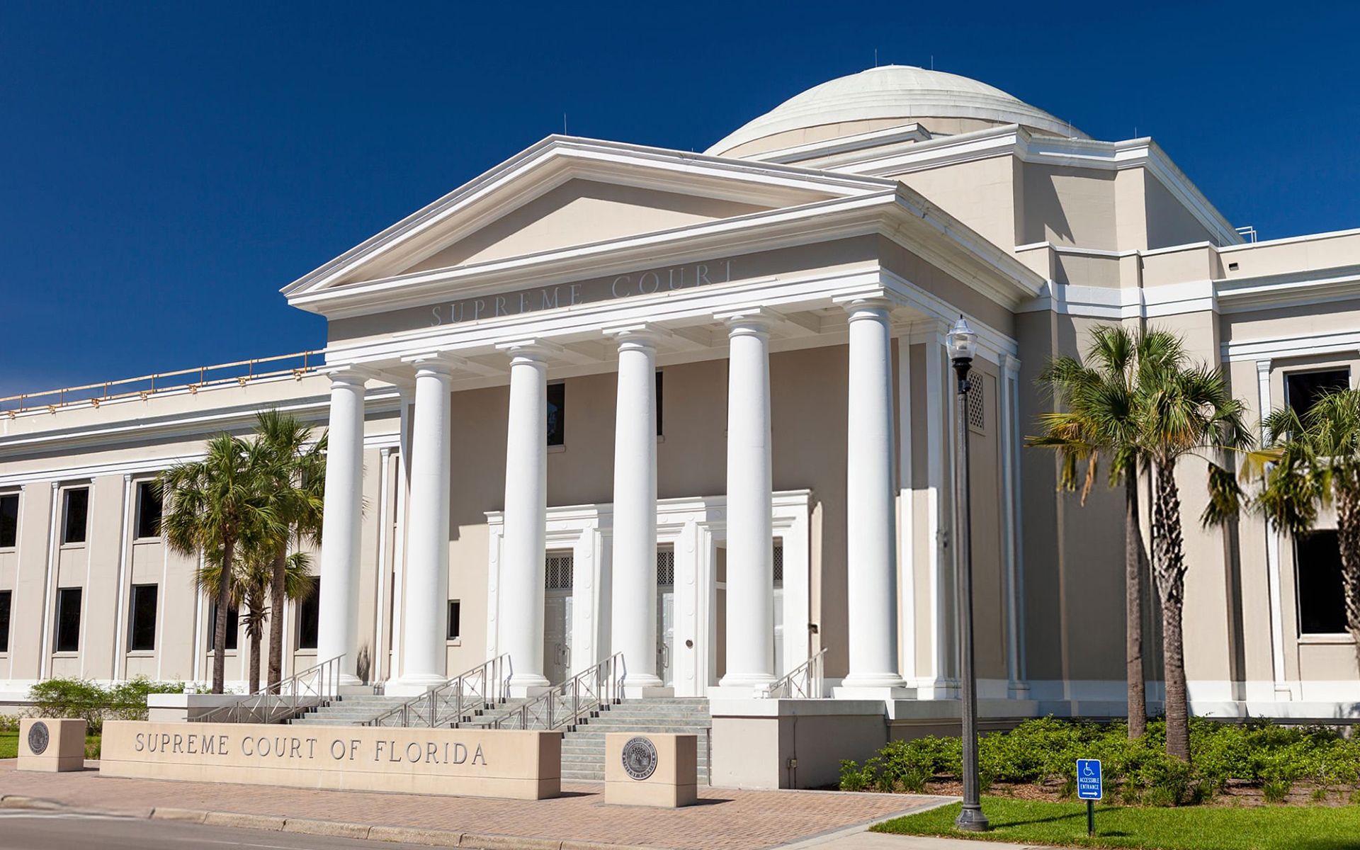 Florida Supreme Court building with white columns and dome, under a clear blue sky.