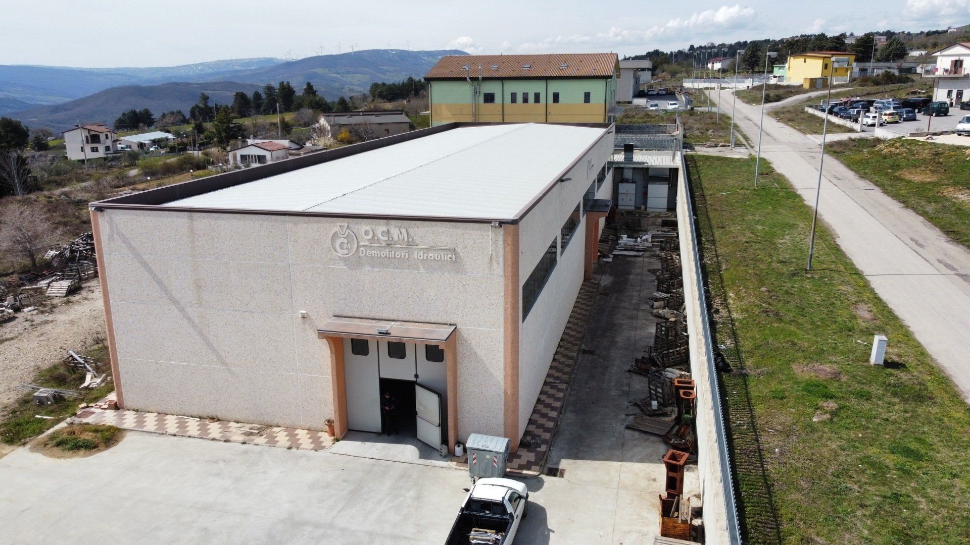 Esterno di un edificio industriale leggero, pareti beige, tetto in lamiera ondulata, insegna