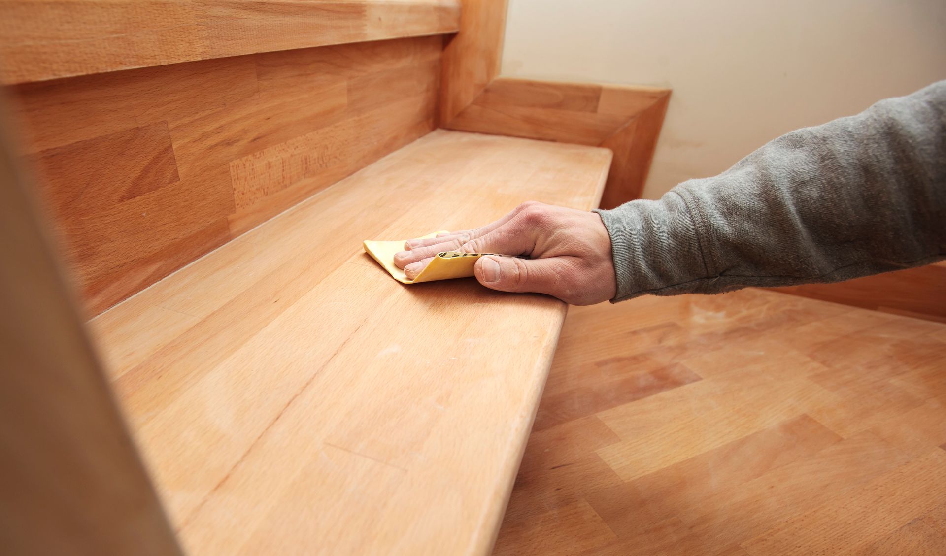 Hand sanding a light wood stair tread with a sanding block Hand sanding a light wood stair tread with a sanding block