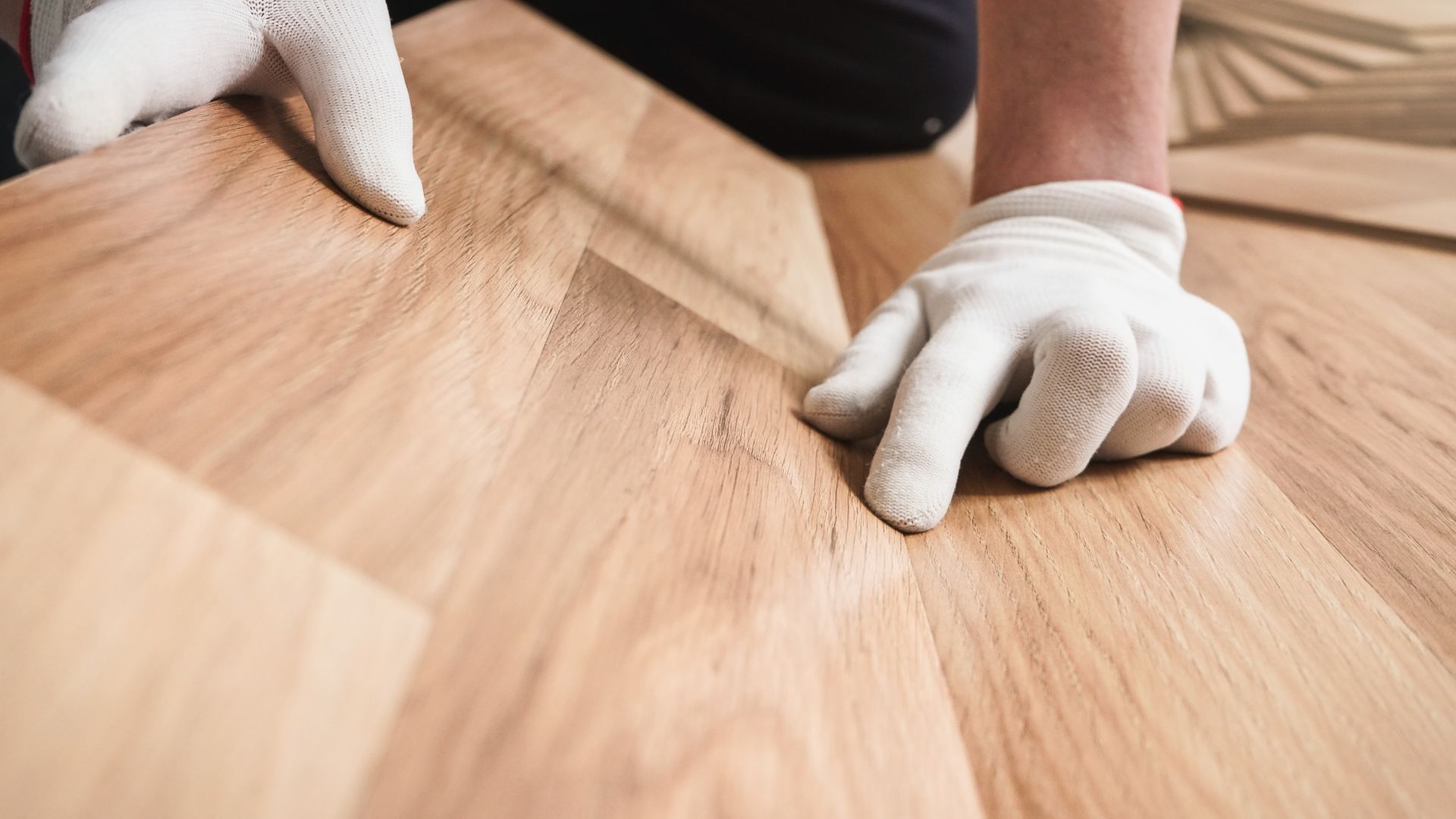 Gloved hands sanding a wooden tabletop in a workshop Gloved hands sanding a wooden tabletop in a workshop