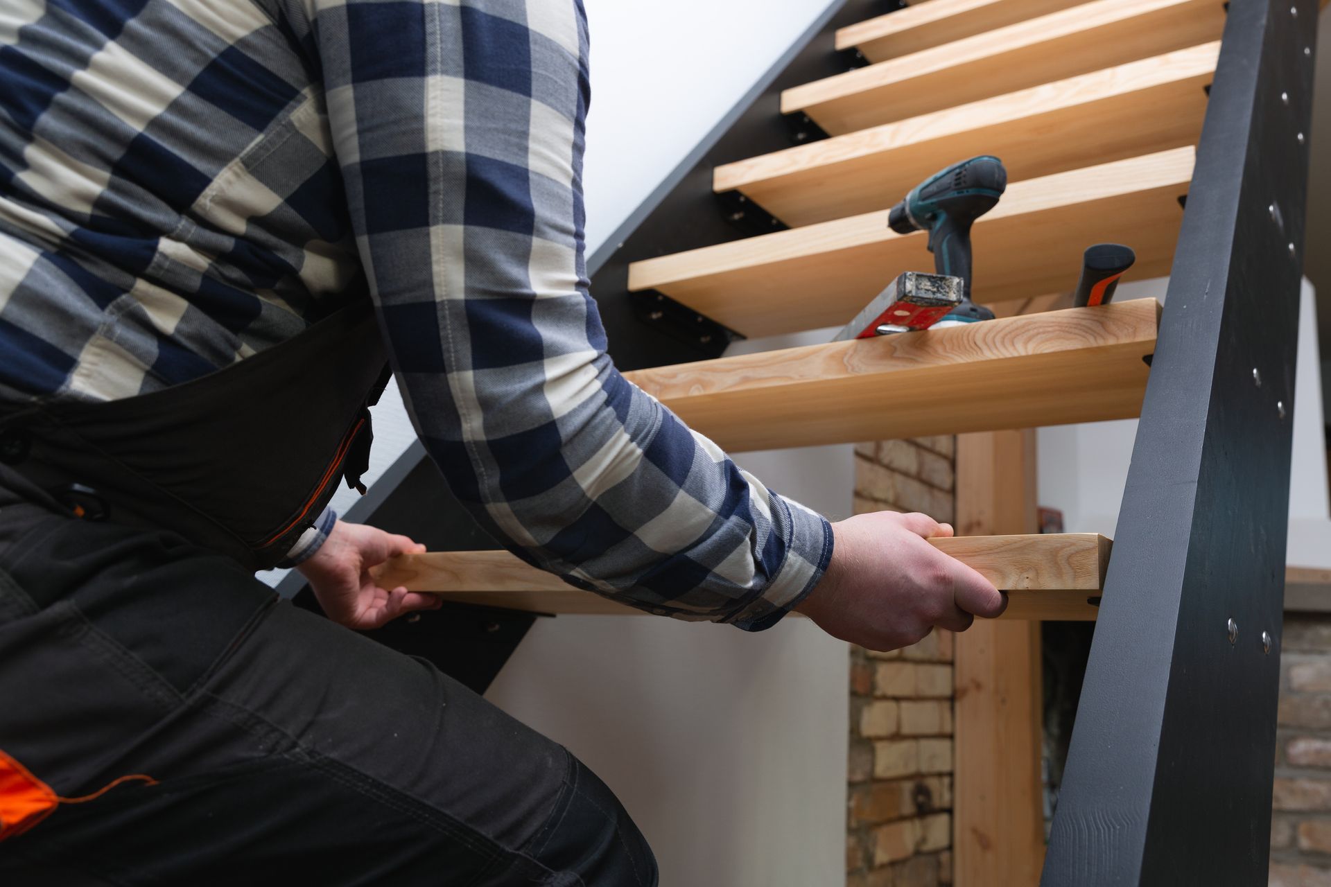 Person installing a wooden stair tread with a drill on an unfinished staircase. Person installing a wooden stair tread with a drill on an unfinished staircase.