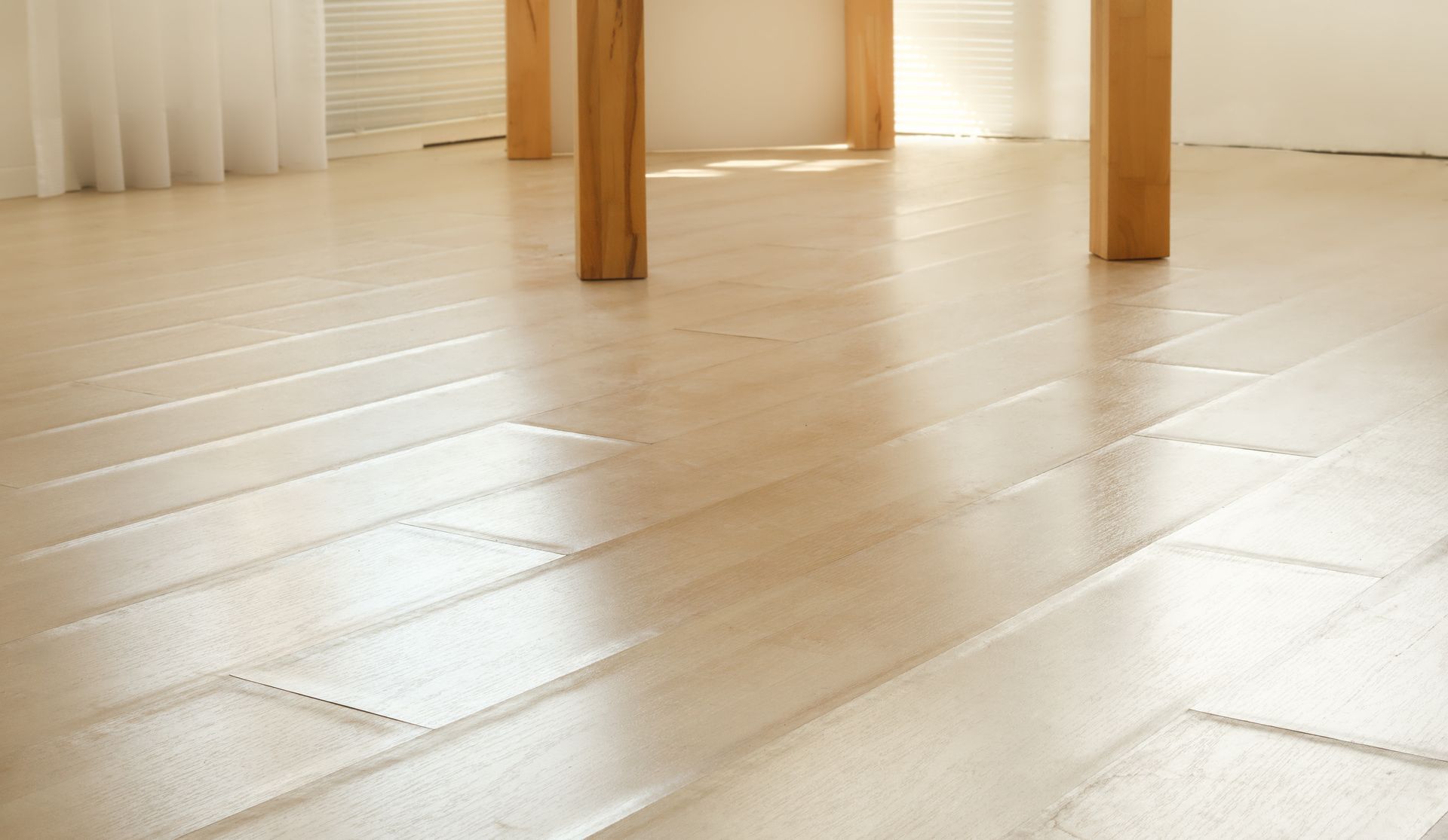 Light wood floor beneath a table with wooden legs in a bright room