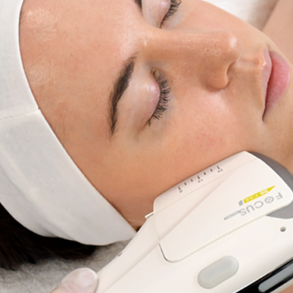 Woman undergoing facial skin tightening treatment with a device, close up.