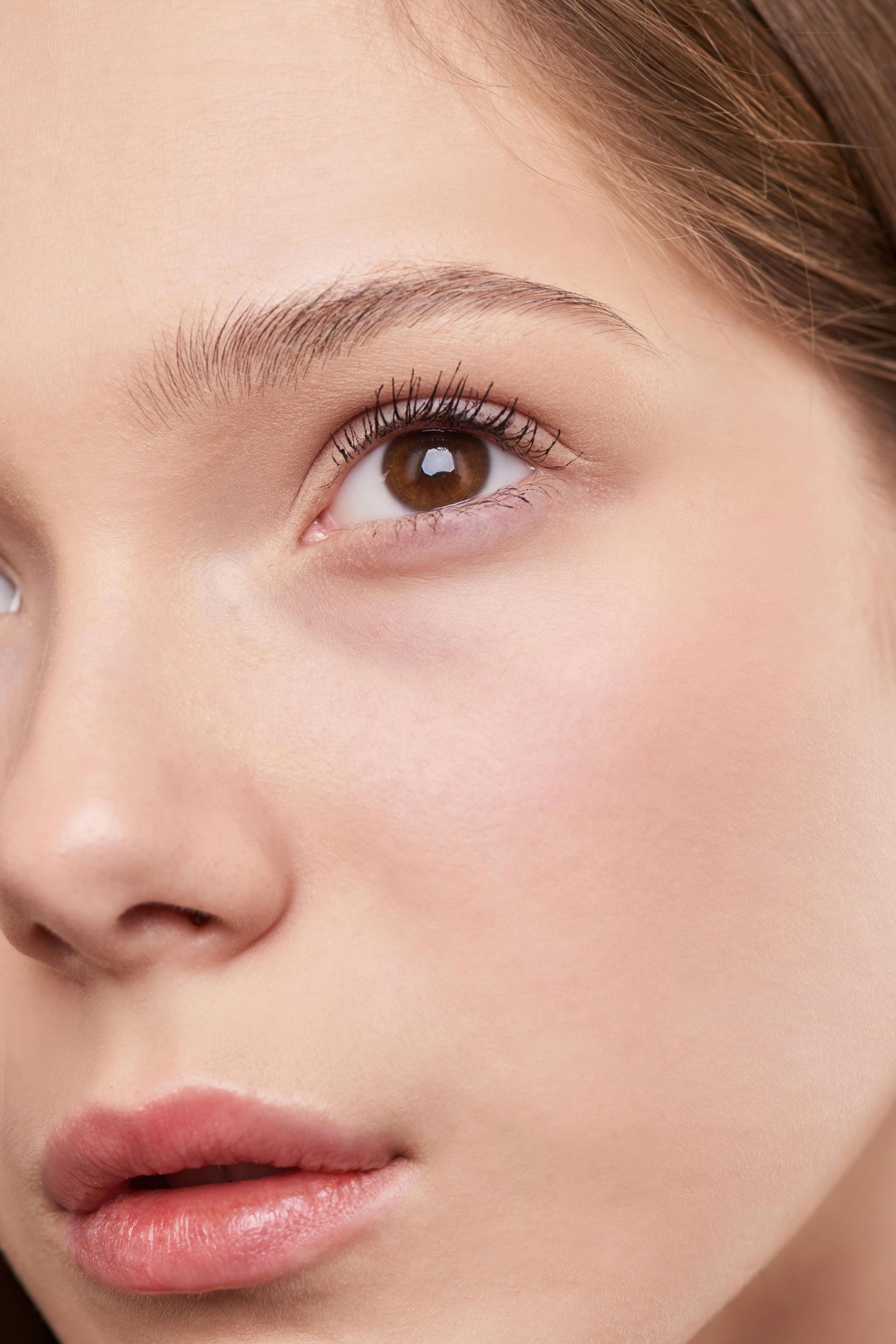 Close-up of a person's face, brown eye, soft pink lips, light skin, neutral makeup.