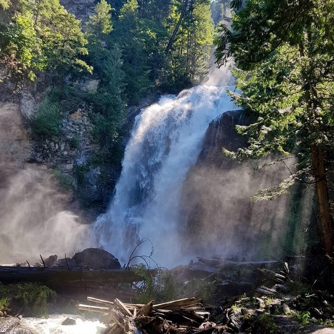 Waterfall cascading into a rocky pool amid dense green forest and mist