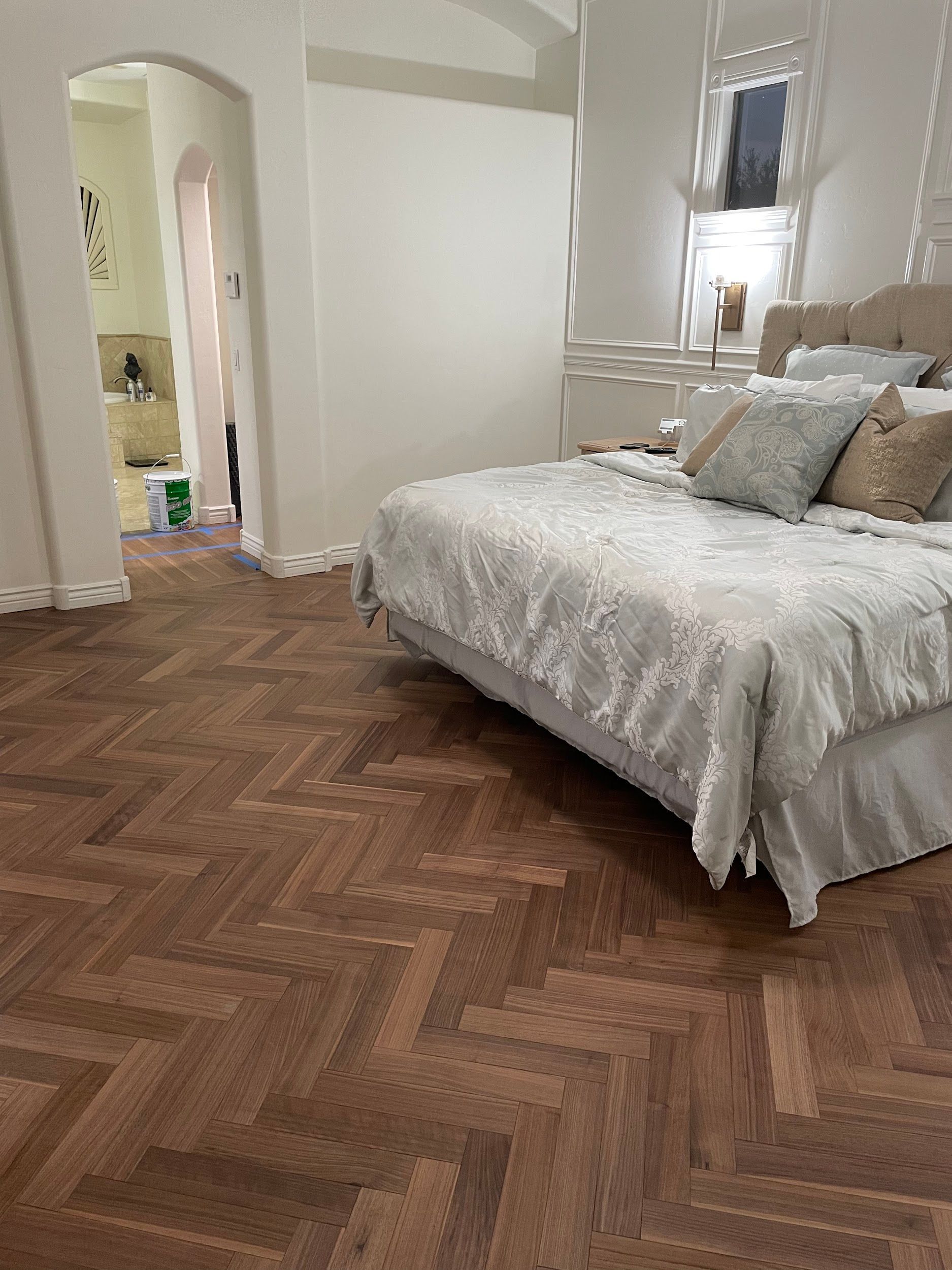 A bedroom with a bed and a wooden floor.