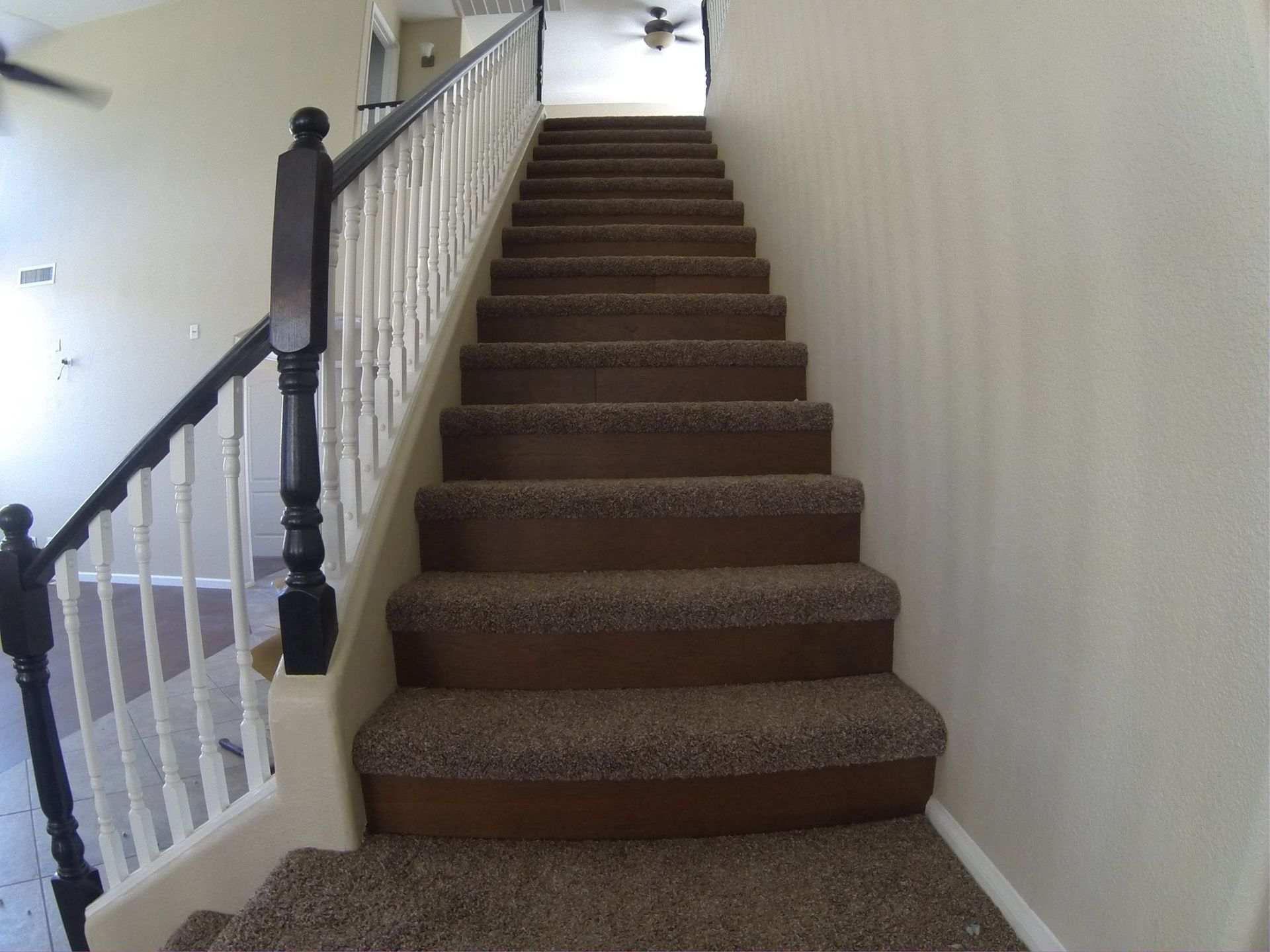 A set of stairs with brown carpet and a white railing