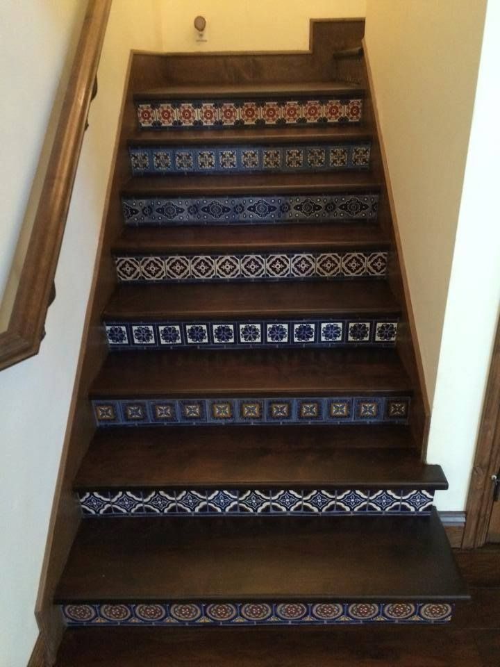 A wooden staircase with blue and white tiles on the steps