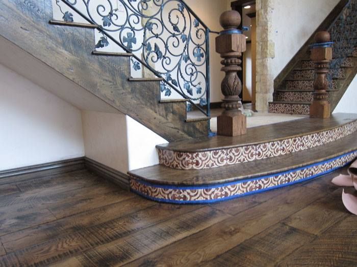 A wooden staircase with a wrought iron railing and a wooden floor