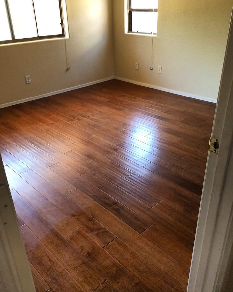 A bedroom with hardwood floors and two windows.