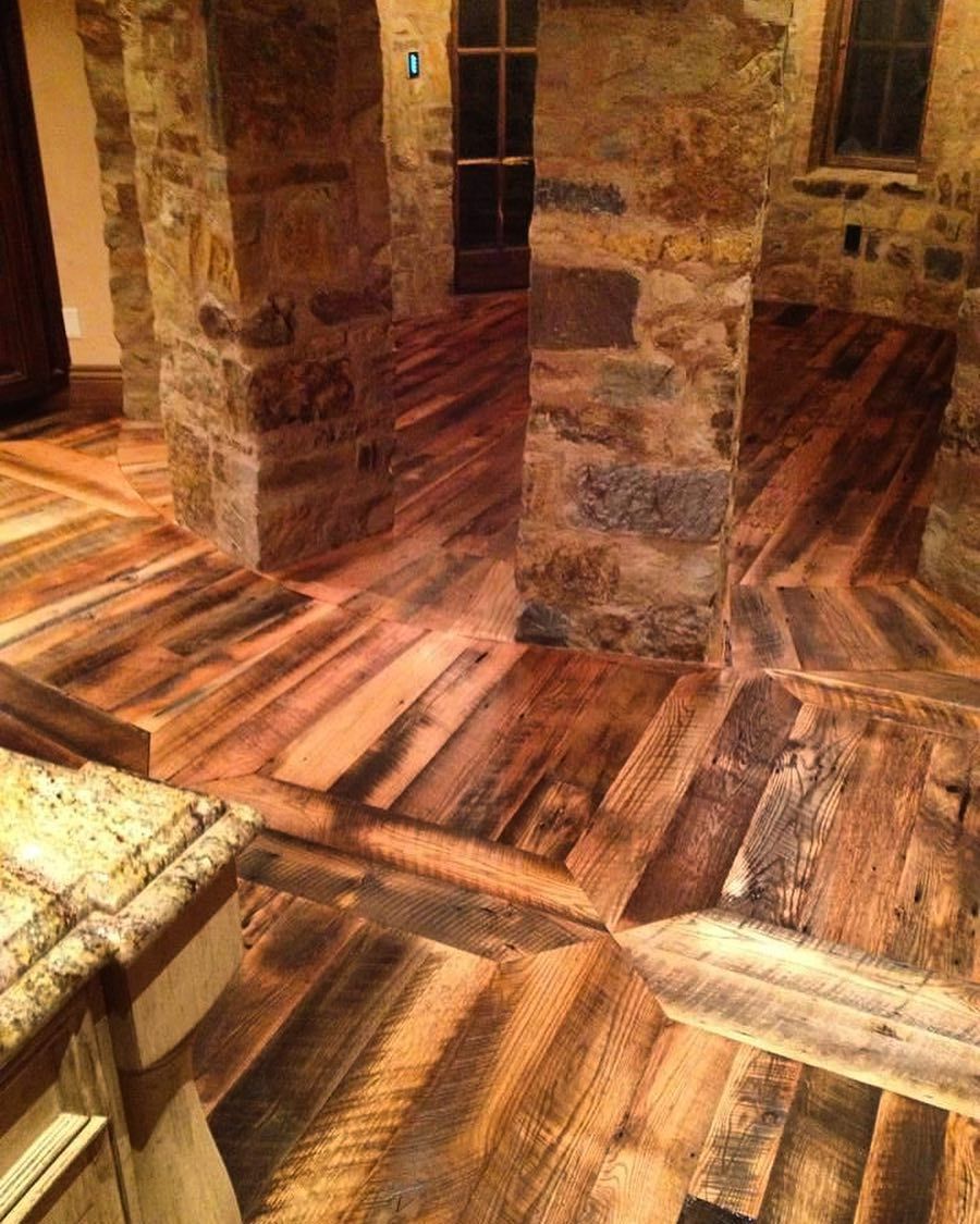 A kitchen with a wooden floor and a stone wall.