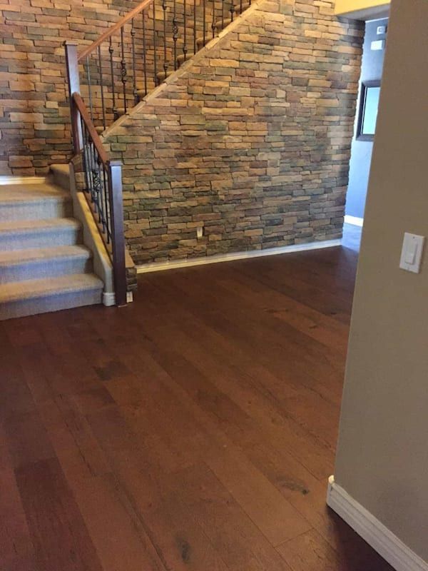 A hallway with stairs and a stone wall