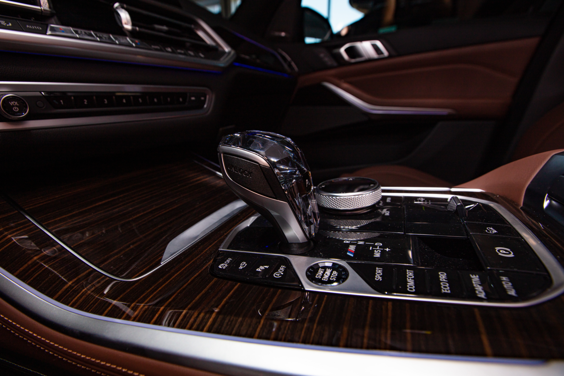Interior car console with wood trim, gear shift, and control dial.