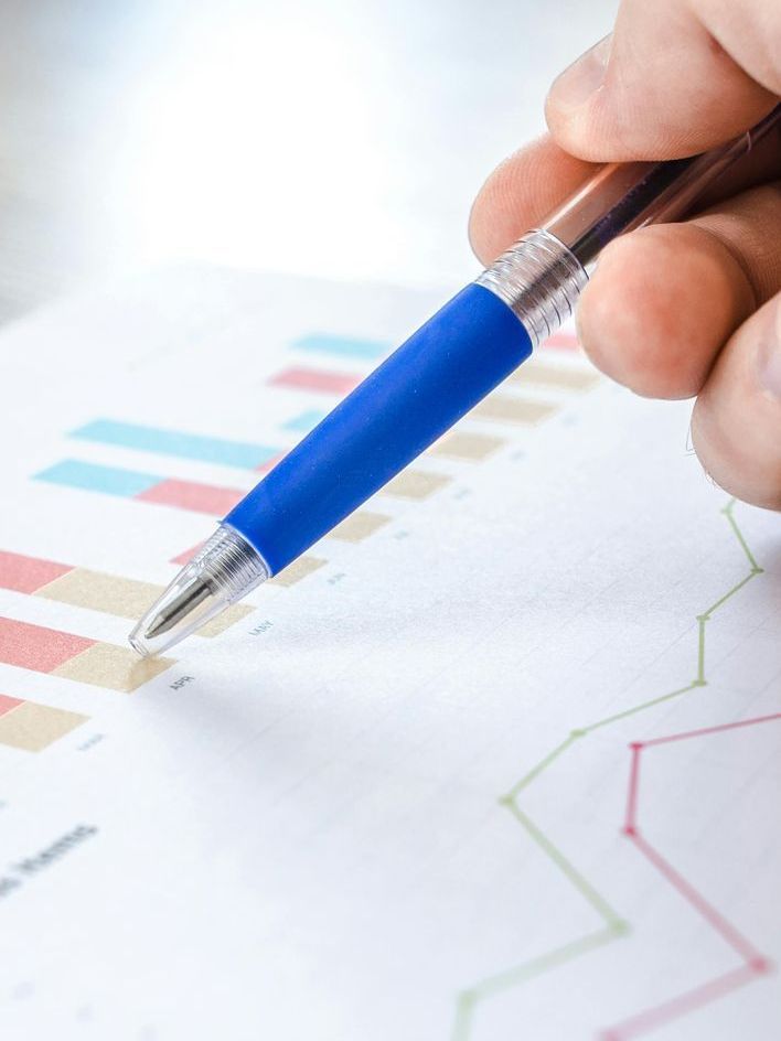 Why Choose A.G. Secure HomeWatch Inc Hand with blue pen pointing at a bar graph and line graph, examining data.