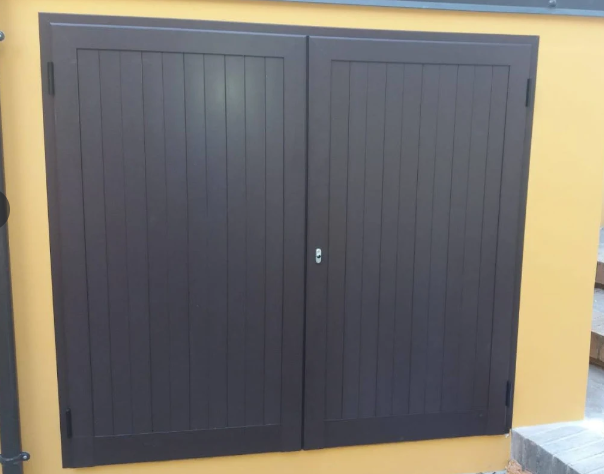 Doppie porte in legno scuro con pannelli verticali su una parete gialla