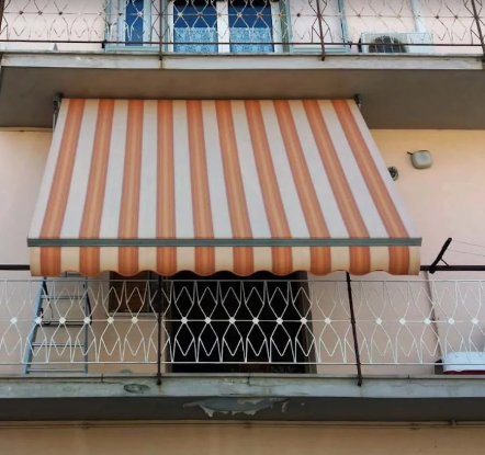 Tenda a righe arancioni e bianche sopra la finestra di un balcone di un condominio.