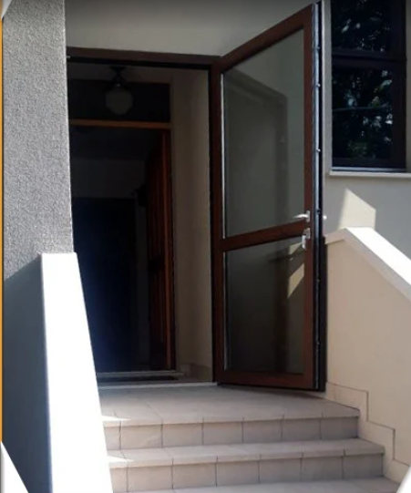 Apertura con porta a vetri che conduce a una breve scala piastrellata all'esterno dell'edificio.