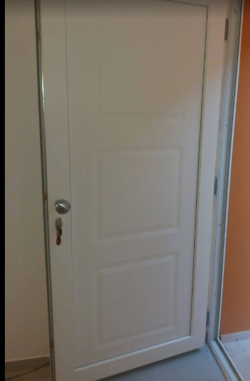 Porta interna bianca con maniglia argentata in un corridoio, parzialmente aperta.