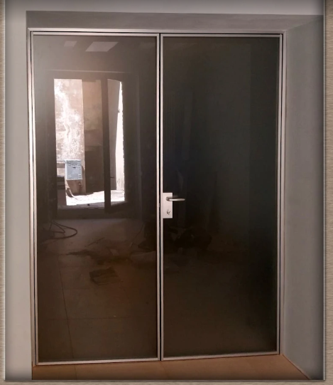Doppie porte in vetro con telaio metallico in un corridoio interno poco illuminato