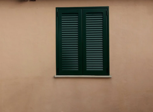 Persiane verde scuro su una parete beige