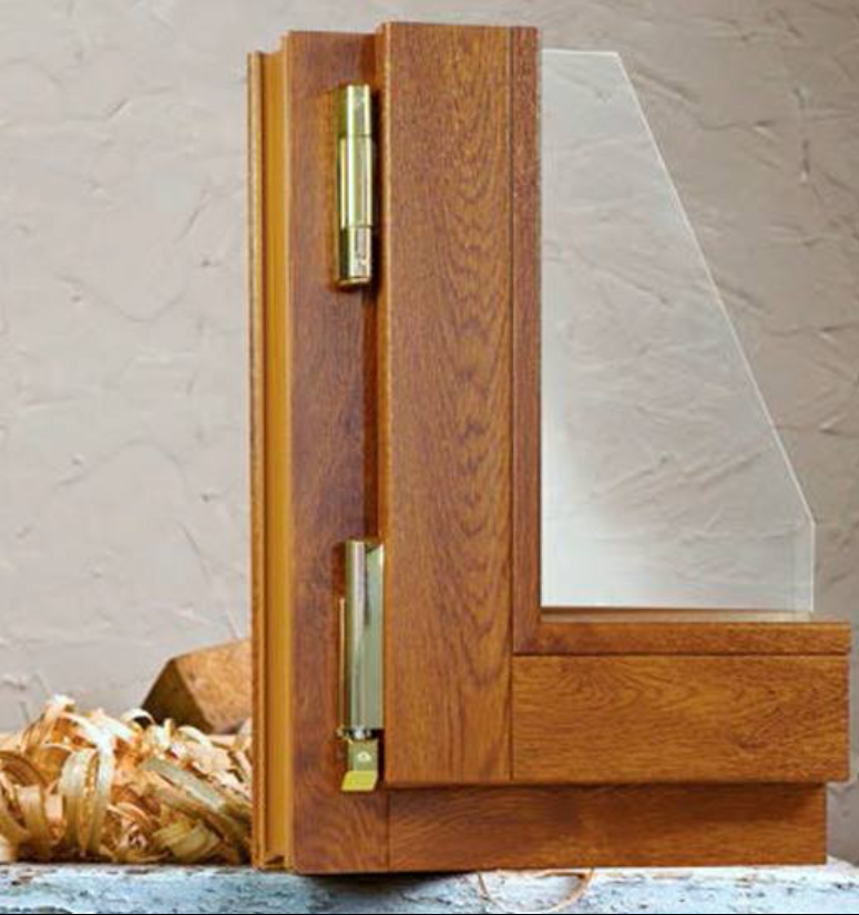 Telaio della finestra in legno con cerniere in ottone e pannello in vetro satinato su una superficie ruvida.